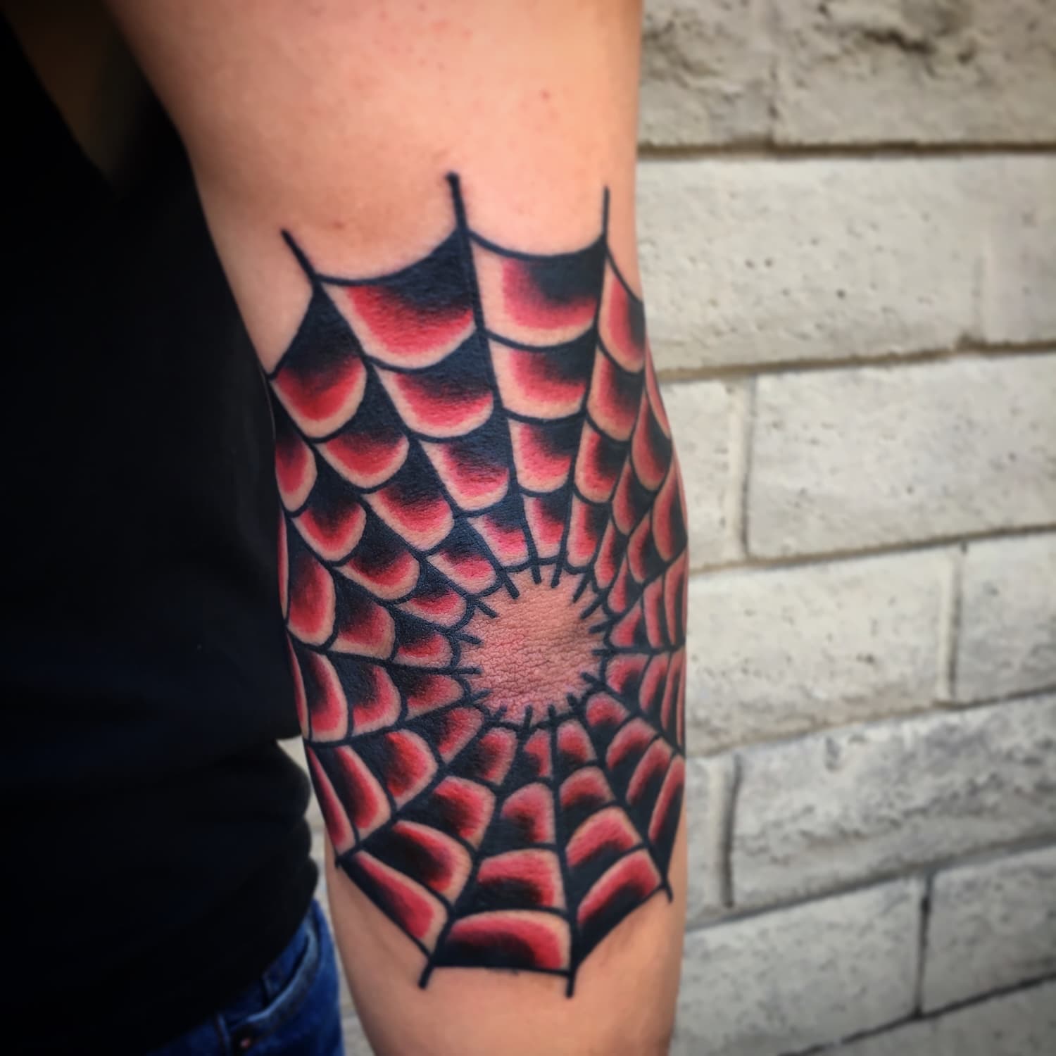 Tattoo of red spiderweb on arm