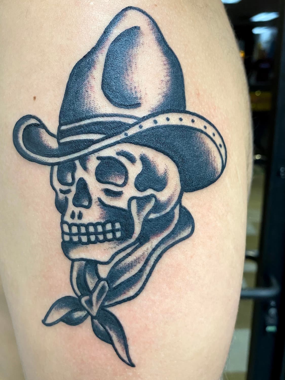 Tattoo of skull with cowboy hat on upper arm