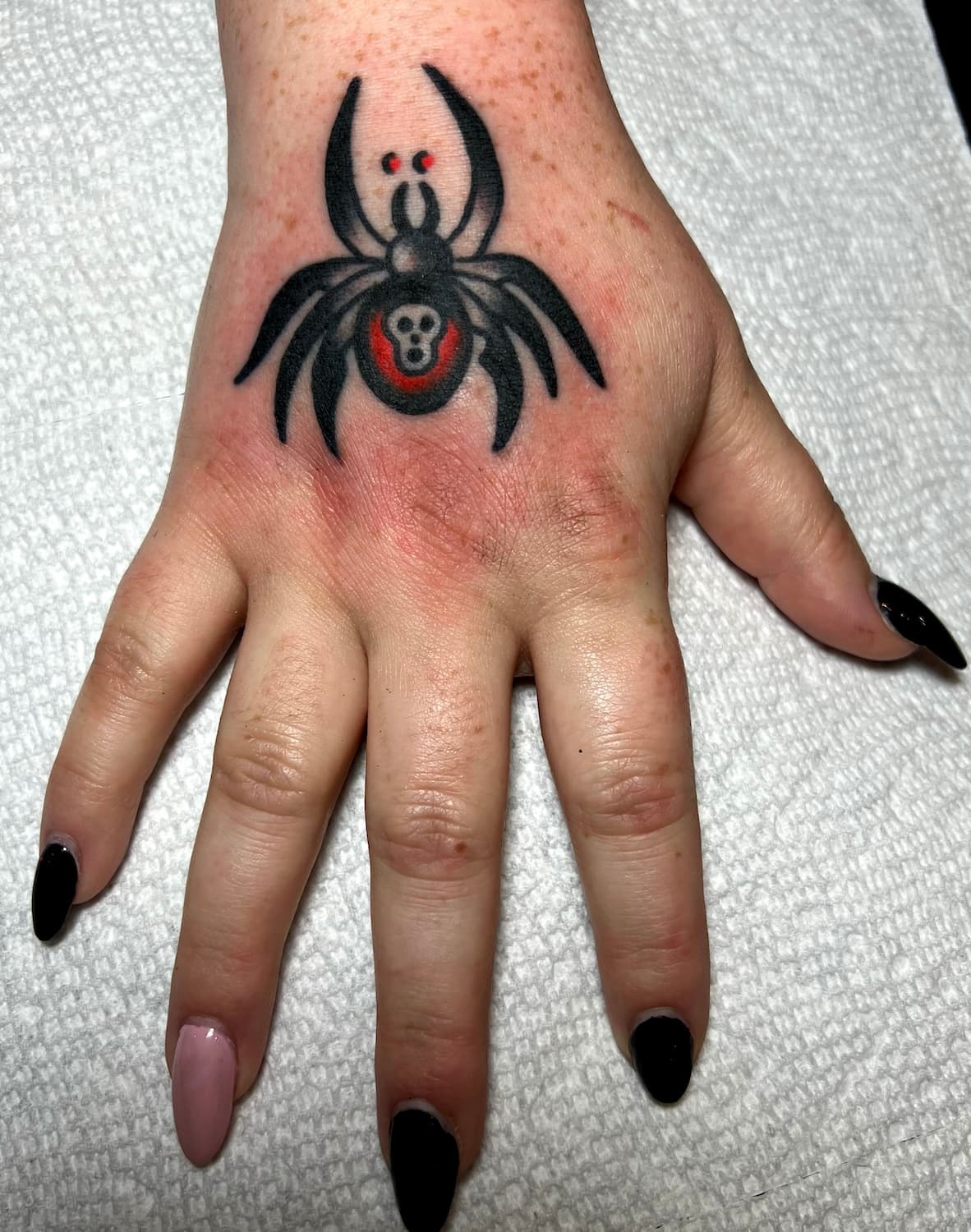 Tattoo of spider on top of hand